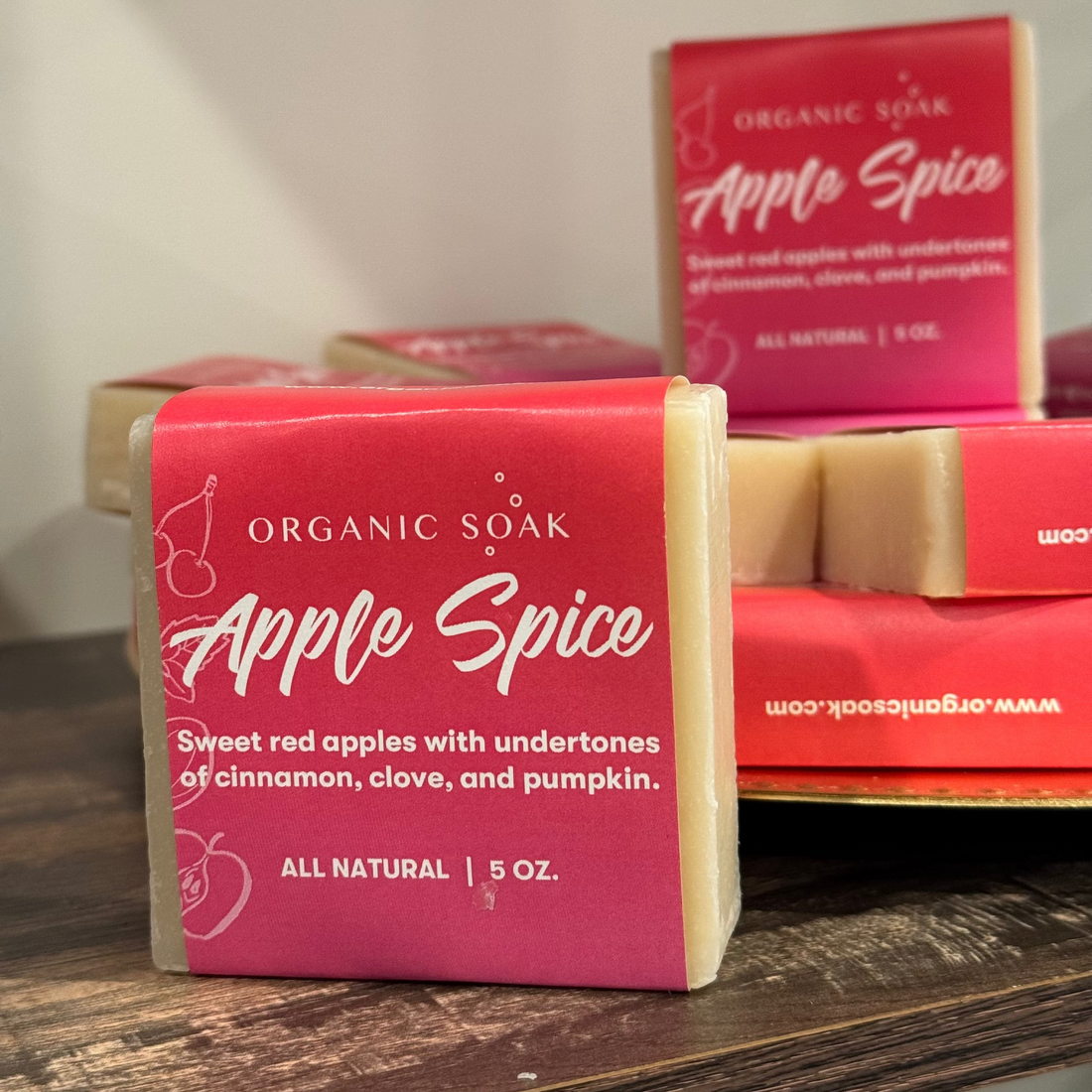 Bar of Organic Soap Apple Spice on a wooden surface with packaging in the background.
