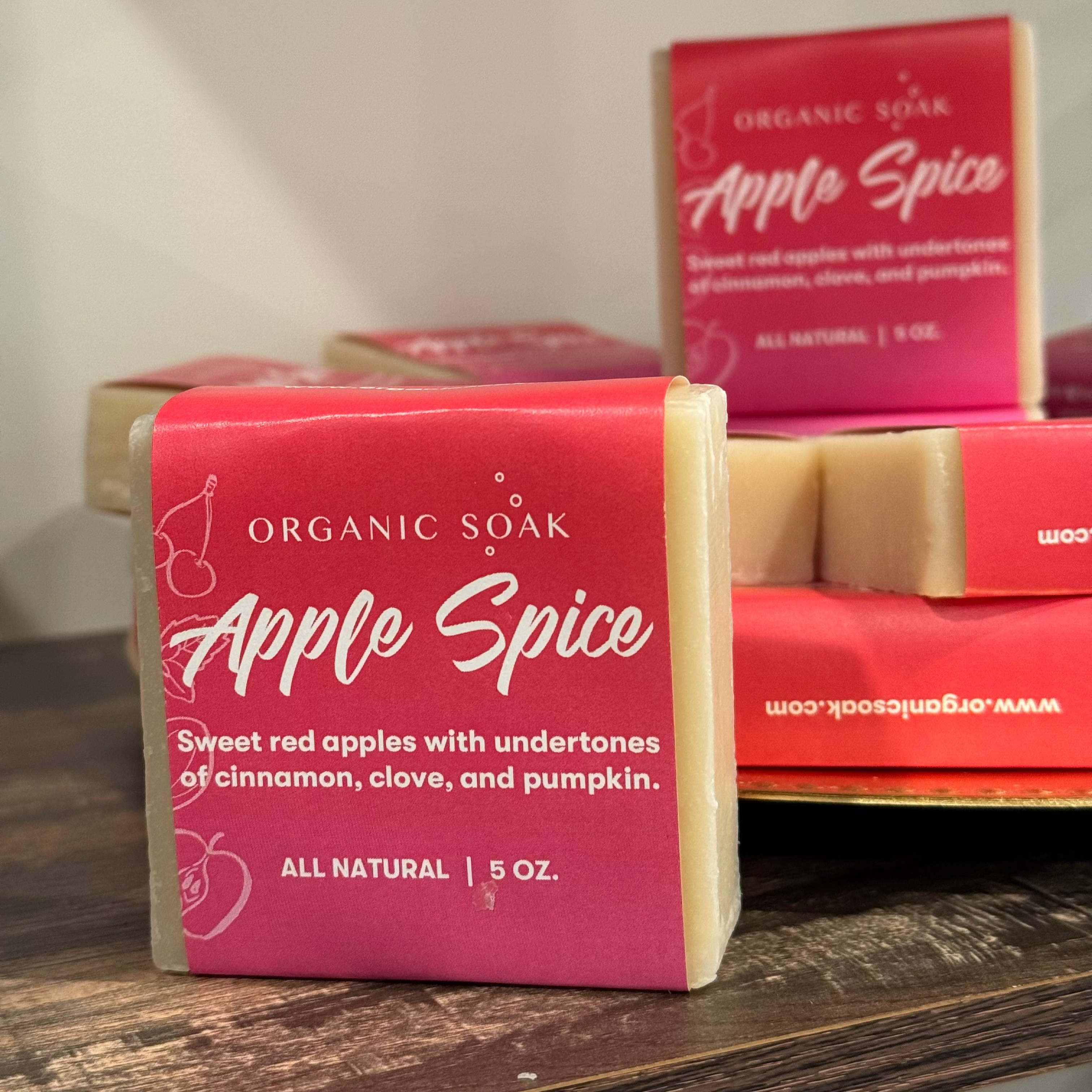 Bar of Organic Soap Apple Spice on a wooden surface with packaging in the background.
