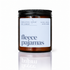 An amber glass jar candle with a black screw-top lid and a white label reading &