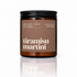 An amber glass jar candle with a black screw-top lid and a brown label reading &
