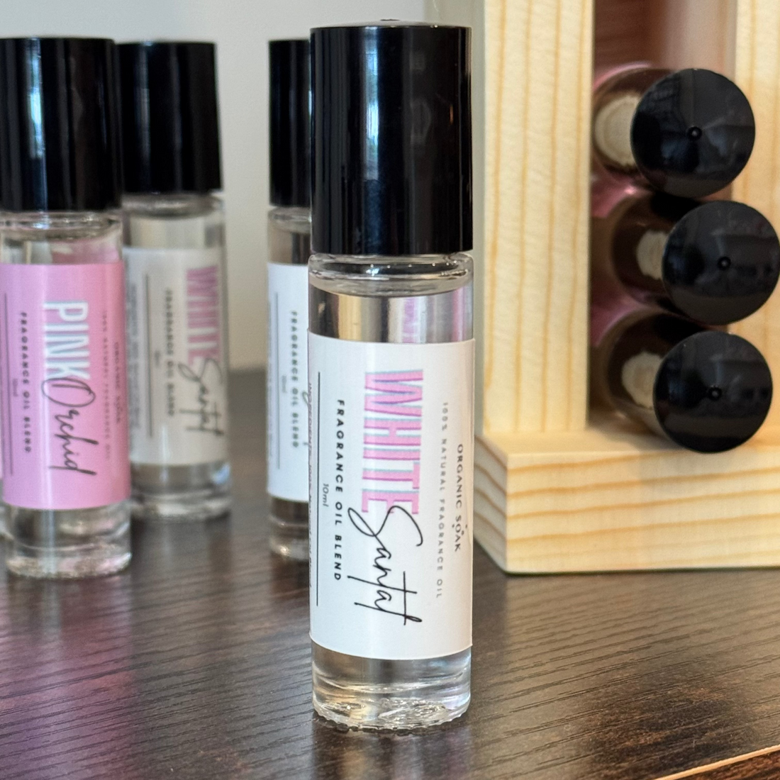 Collection of perfume bottles on a wooden surface with a wooden display rack in the background.