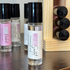 Collection of perfume bottles on a wooden surface with a wooden display rack in the background.