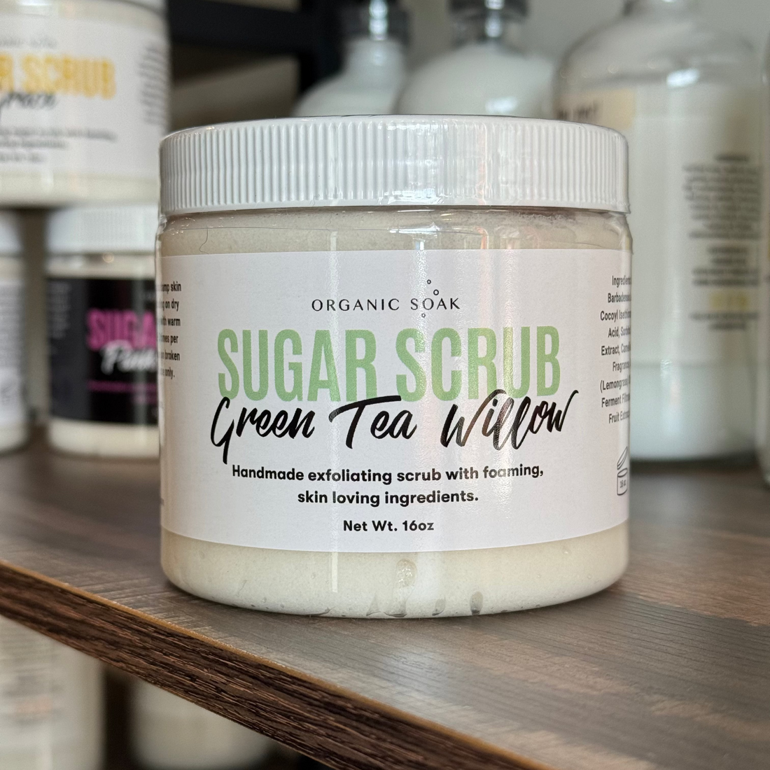 Jar of Organic Soak Sugar Scrub with Green Tea Willow on a shelf with other products.