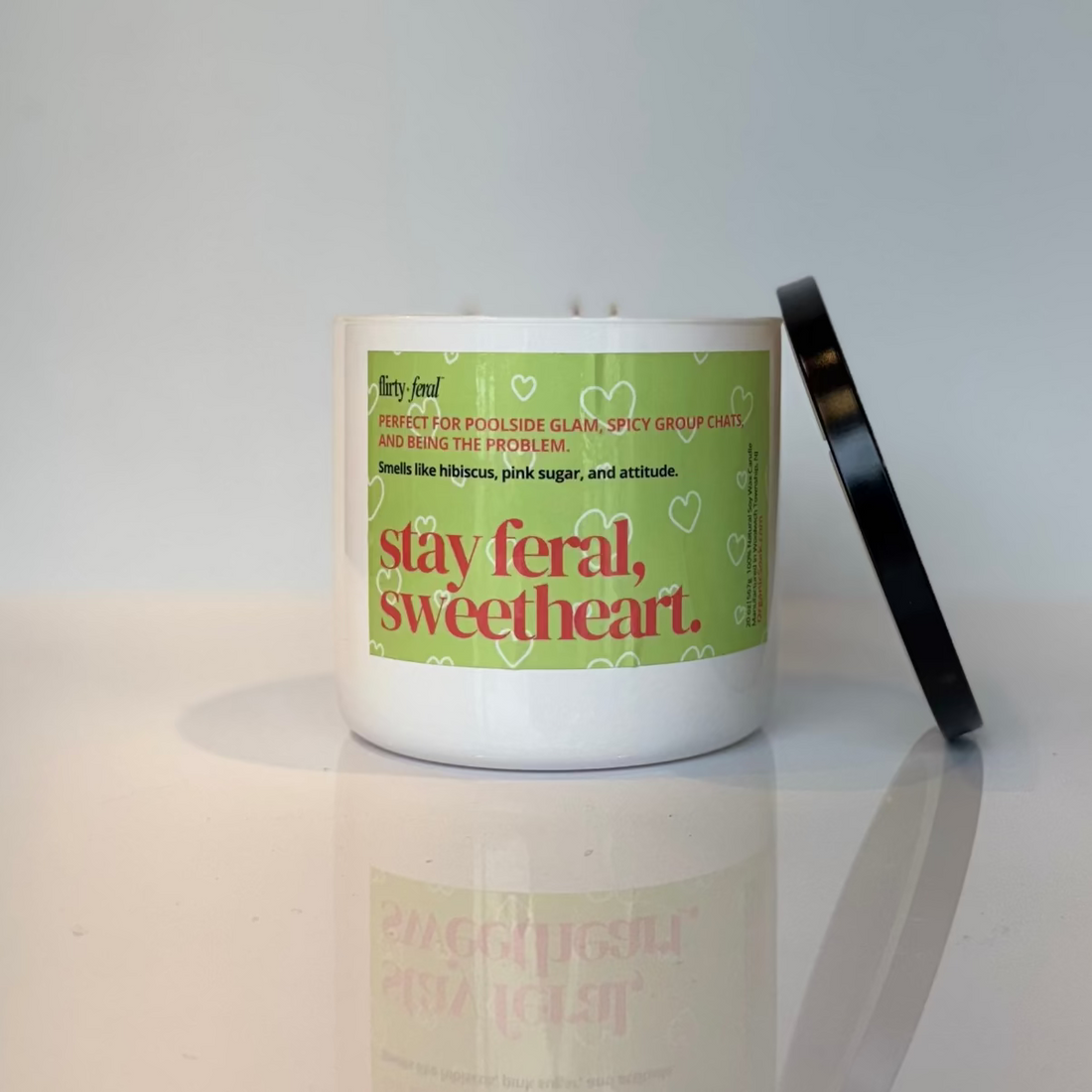 Soy candle with a  green label on a reflective white surface