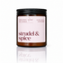 An amber glass jar candle with a black screw-top lid and a pale pink label reading &